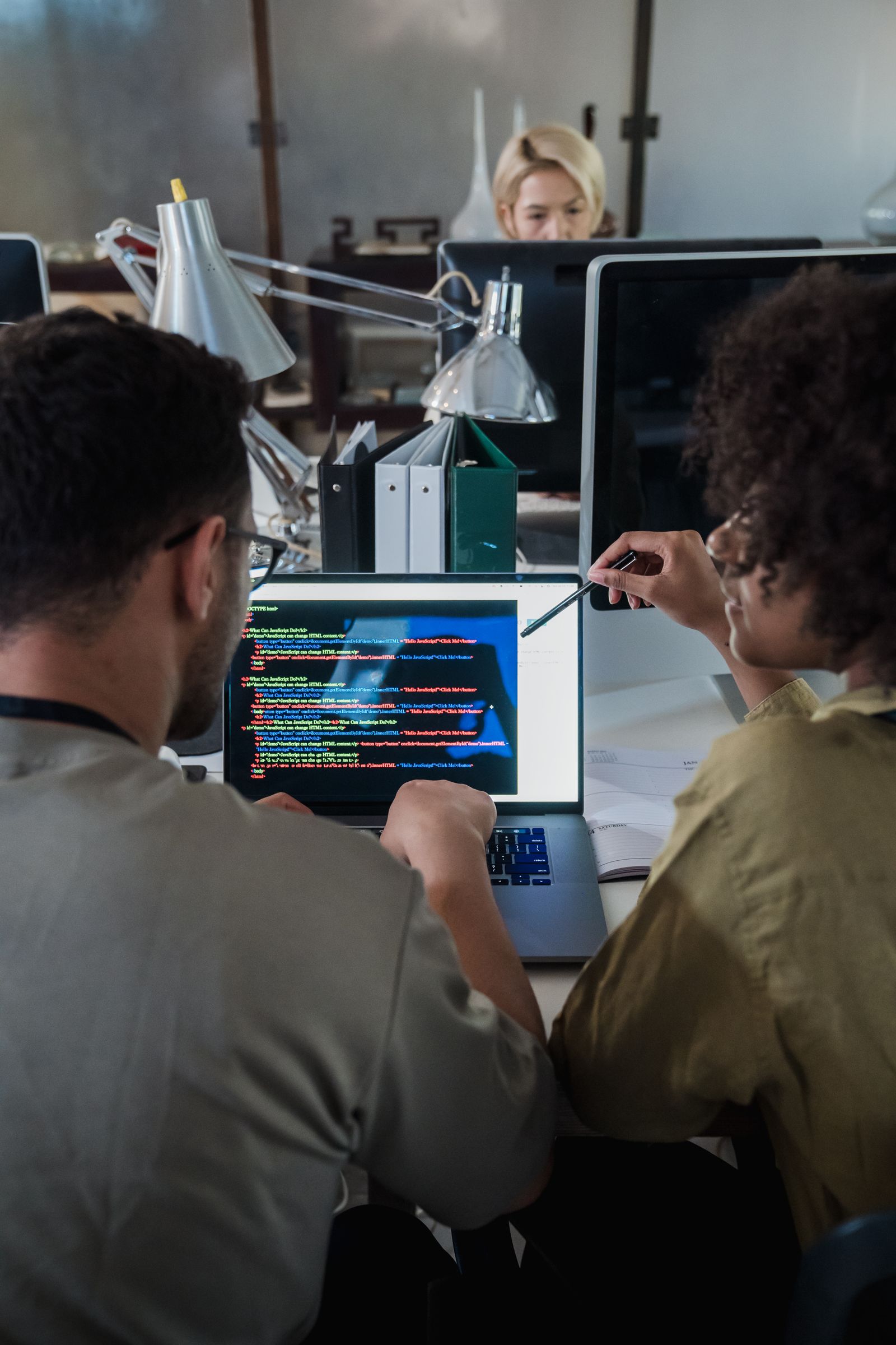 Two colleagues reviewing code on a laptop